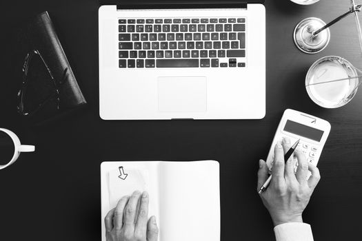 justice and law concept.businessman or lawyer or accountant working on accounts using a calculator and laptop computer and documents in modern office,black and white