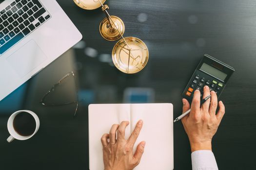 justice and law concept.businessman or lawyer or accountant working on accounts using a calculator and laptop computer and documents in modern office