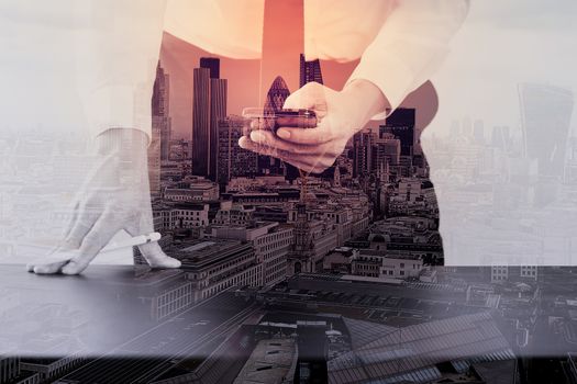 close up of businessman working with smart phone on wooden desk in modern office with London city exposure