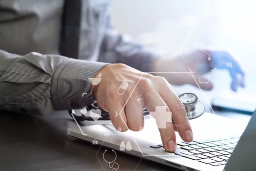 close up of smart medical doctor working with laptop computer and stethoscope on dark wooden desk with virtual reality icon diagram