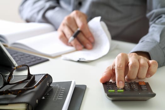 businessman hand working with finances about cost and calculator and latop with mobile phone on withe desk in modern office 