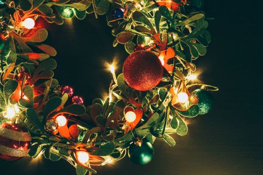 Greeting Season concept.Christmas wreath with decorative light on dark wood background