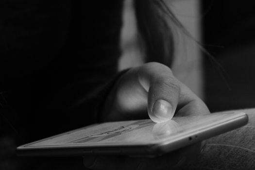 A woman uses a smart phone. Hands and phone close-up. Black and white image