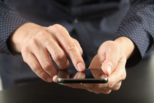 close up of businessman hand working with mobile phone in modern office