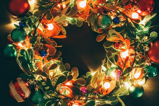 Greeting Season concept.Christmas wreath with decorative light on dark wood background