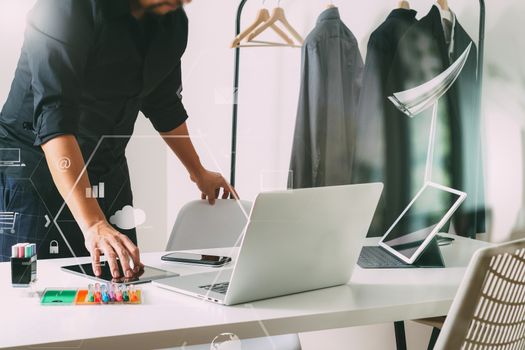 Fashion designer talking mobile phone and using laptop with digital tablet computer in modern studio with VR icon diagram