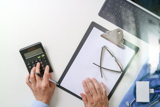 top view of Healthcare costs and fees concept.Hand of smart doctor used a calculator for medical costs in modern hospital 