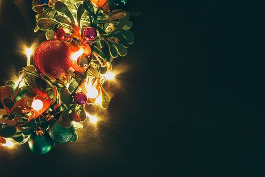 Greeting Season concept.Christmas wreath with decorative light on dark wood background