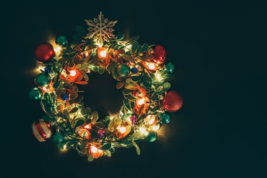 Greeting Season concept.Christmas wreath with decorative light on dark wood background