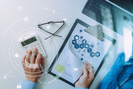 top view of Healthcare costs and fees concept.Hand of smart doctor used a calculator for medical costs in modern hospital with VR icon diagram