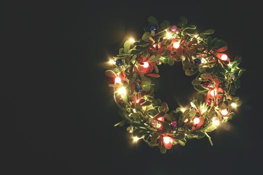 Greeting Season concept.Christmas wreath with decorative light on dark wood background