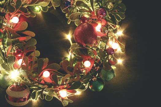 Greeting Season concept.Christmas wreath with decorative light on dark wood background