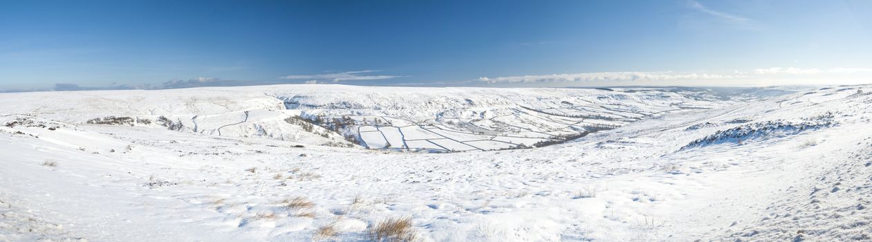 Panoramic view over a snowy winter english countryside rural landscape with fields and meadows