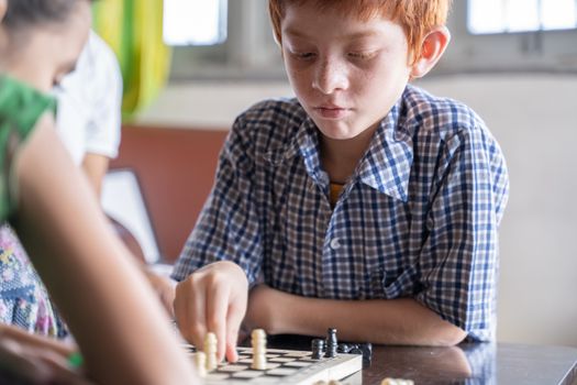 Serious chess player kid thinking and moving coin at home - Concept of kid concentration of game during Early development, home educational games for children.