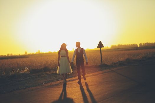 The bride and groom hold hands, hug each other and walk in the park. Sunset light. wedding. Happy love concept. High quality photo