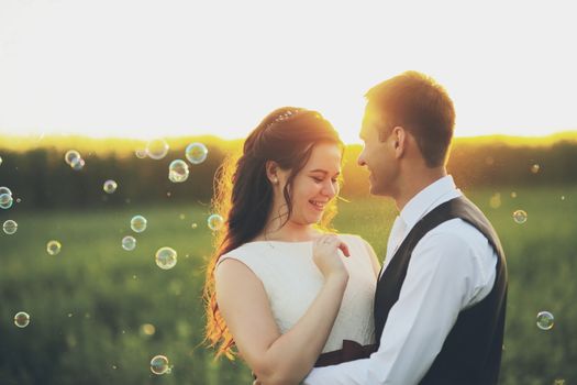 Happy bride and groom hug each other in the park at sunset. Soap bubbles. Wedding. Happy love concept. High quality photo