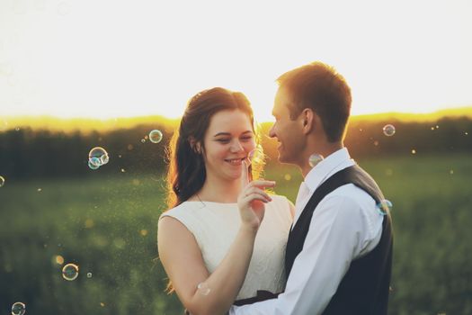 Happy bride and groom hug each other in the park at sunset. Soap bubbles. Wedding. Happy love concept. High quality photo