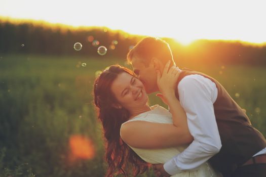 Happy bride and groom hug each other in the park at sunset. Soap bubbles. Wedding. Happy love concept. High quality photo