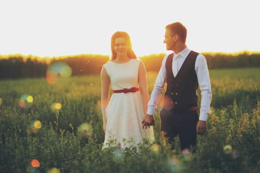 The bride and groom hold hands and walk in the park. Sunset light. Bubble. Wedding. Happy family concept. High quality photo