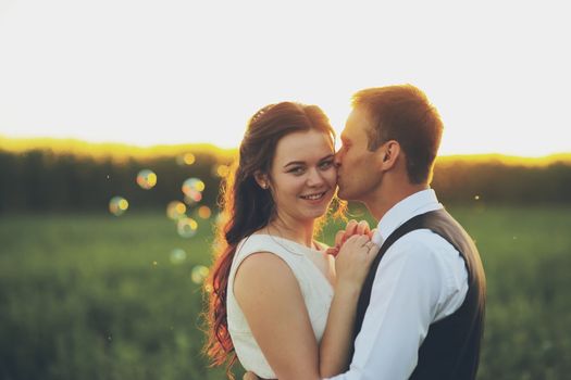 Happy bride and groom hug each other in the park at sunset. Soap bubbles. Wedding. Happy love concept. High quality photo