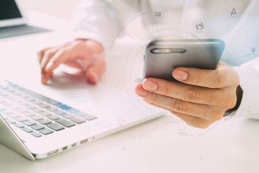 close up of businessman using mobile phone and laptop computer on white desk in modern office with VR icons diagram