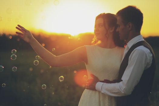 Happy bride and groom hug each other in the park at sunset. Soap bubbles. Wedding. Happy love concept. High quality photo