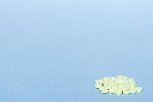 handful of yellow pills on a blue background. concept of healthcare, medicine, vitamins. background, free space, copy space. blurry background. soft focus.cluster of yellow pills on a blue background