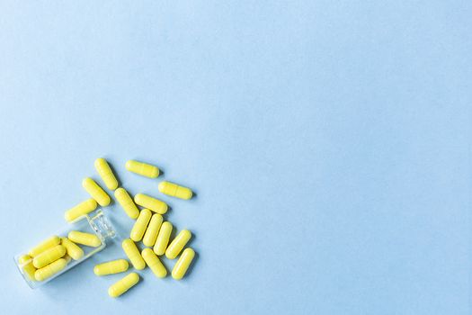 Yellow capsules are poured out of a bottle on a blue background. Omega-3 vitamins. food Supplement. space for text. copy space. blurred background. Selective focus. concept of medicine. Free space.