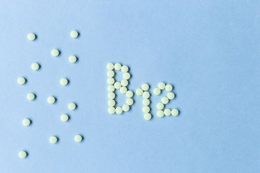 Yellow pills forming shape to B12 alphabet on blue background. Vitamin complex. Concept, health care, healthy nutrition. Healthy lifestyle. Food additive. copy space. Soft focus. blurry background.