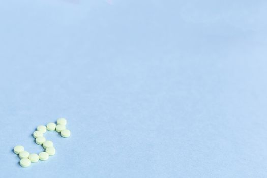 tablets in the form of a dollar sign on a blue background. Concept of a dollar sign made with vitamin tablets on a blue background.banner. copy space. soft focus, blurry background. space for text.