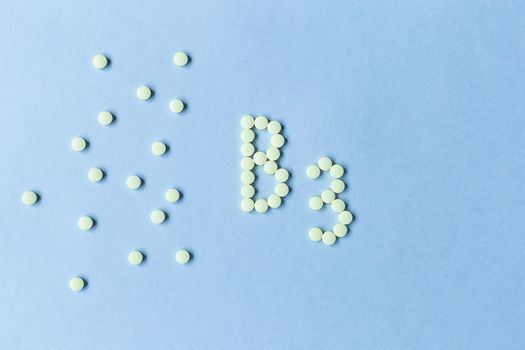 Yellow pills forming shape to B3 alphabet on blue background, banner. free space. copy space. soft focus, blurry background. nutritional supplements, healthy food, health maintenance. space for text.