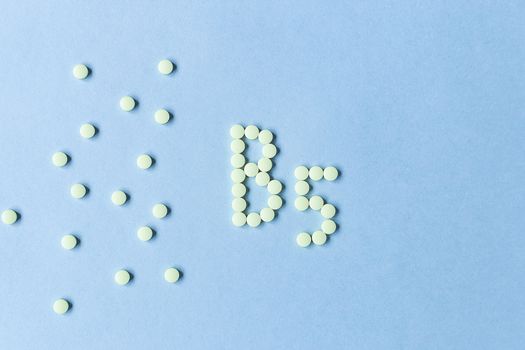 Yellow tablets forming B5 on a blue background. Vitamin complex. Concept, health care, healthy nutrition. Medicine. Healthy lifestyle. Food additive. copy space. Soft focus. blurry background. poster