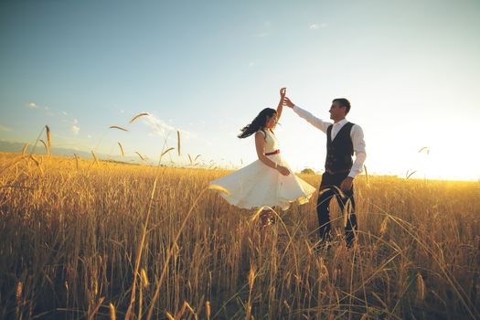 The bride and groom hold hands dancing in the park. Sunset light. wedding. Happy love concept. High quality photo