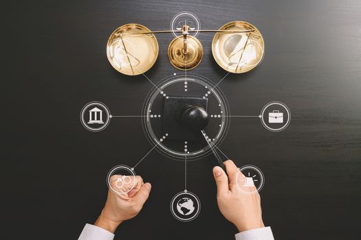 justice and law concept.Top view of Male judge hand in a courtroom with the gavel and brass scale on dark wood table with Vr diagram