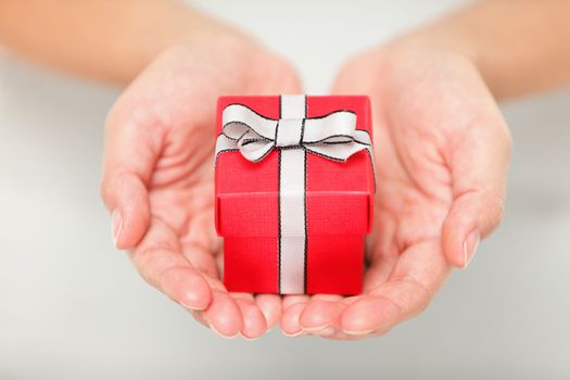 Gift. Woman holding showing gift or christmas gift in her hands. Female hands giving red present.