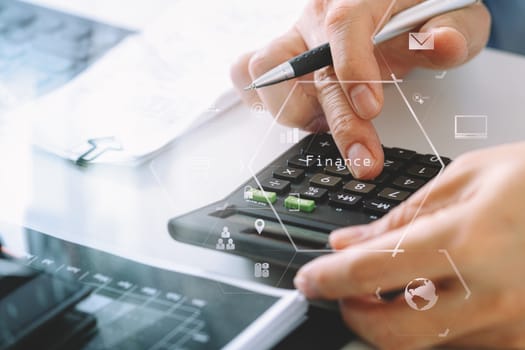 close up of businessman hand working with finances about cost and calculator and latop with mobile phone on withe desk in modern office with VR icon diagram