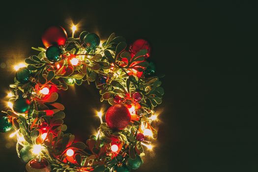 Greeting Season concept.Christmas wreath with decorative light on dark wood background