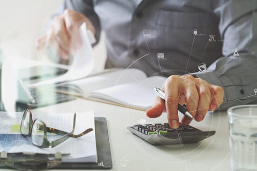 businessman hand working with finances about cost and calculator and latop with mobile phone on withe desk in modern office with VR icon diagram