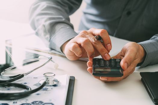 Healthcare costs and fees concept.Hand of smart doctor used a calculator for medical costs in modern hospital 