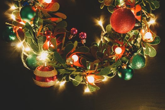 Greeting Season concept.Christmas wreath with decorative light on dark wood background