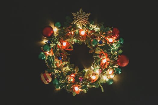 Greeting Season concept.Christmas wreath with decorative light on dark wood background