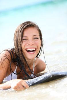 Surfboard laughing pretty mixed race, asian caucasian woman ashore - playfully, wet - enjoying holiday. Hawaii, USA