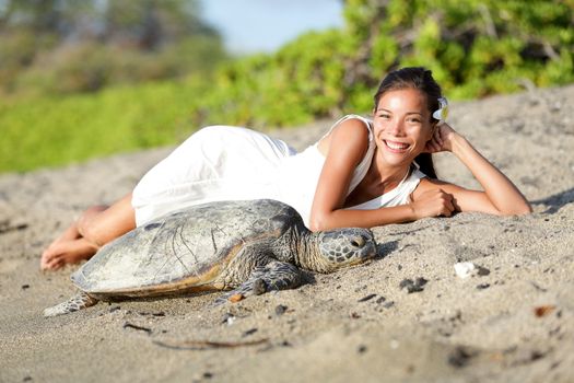 Turtle on beach - pretty asian caucasian mixed race woman wearing white dress lying beside. Sun shining in relaxed atmosphere. Nature scene with sea turtles, Big Island, Hawaii