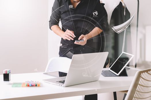 Fashion designer working with mobile phone and using laptop with digital tablet computer in modern studio with VR icon diagram