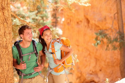 Hiking - young couple of hikers relaxing resting in Bryce Canyon walking smiling happy together. Multiracial couple, young Asian woman and Caucasian man in Bryce Canyon National Park landscape, Utah