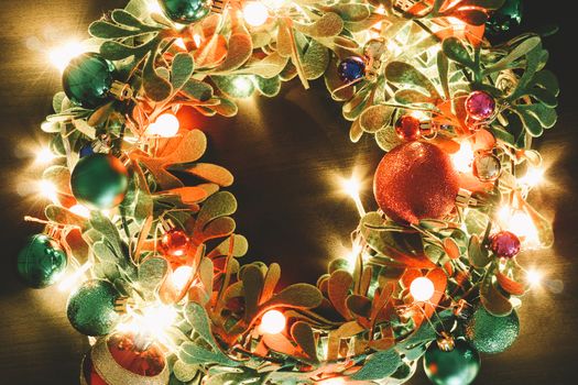 Greeting Season concept.Christmas wreath with decorative light on dark wood background