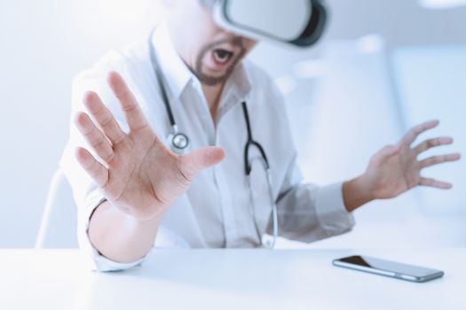 smart doctor wearing virtual reality goggles in modern office with mobile phone using with VR headset 