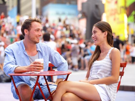 Dating couple, New York, Manhattan, Times Square dating drinking coffee smiling happy sitting at red tables enjoying their tourism vacation travel in the USA. Asian woman, Caucasian man.