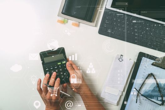 top view of businessman hand working with finances about cost and calculator and latop with mobile phone on withe desk in modern office with VR icon diagram