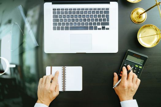 justice and law concept.businessman or lawyer or accountant working on accounts using a calculator and laptop computer and documents in modern office